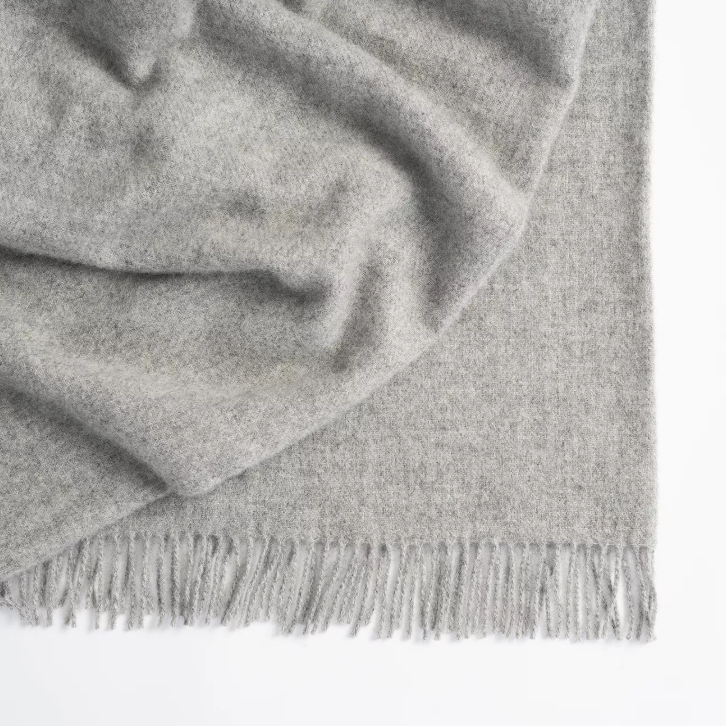 Shop the Nevis lambswool throw 130x200cm – made from 100% New Zealand wool with a soft, thick texture and tassel fringe, perfect for cosy living and gifting.