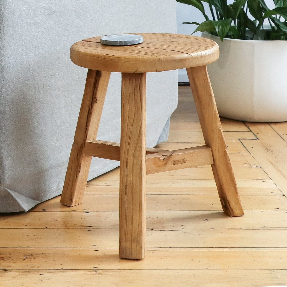 A handcrafted reclaimed elm stool with rustic character, designed to function as seating, a bedside, or a side table.