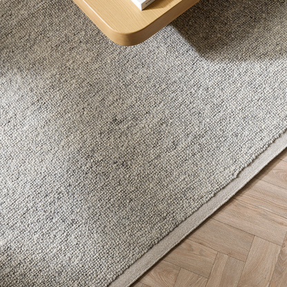 Beige rug on a wooden floor with a small round table in the corner. 100% NZ Wool