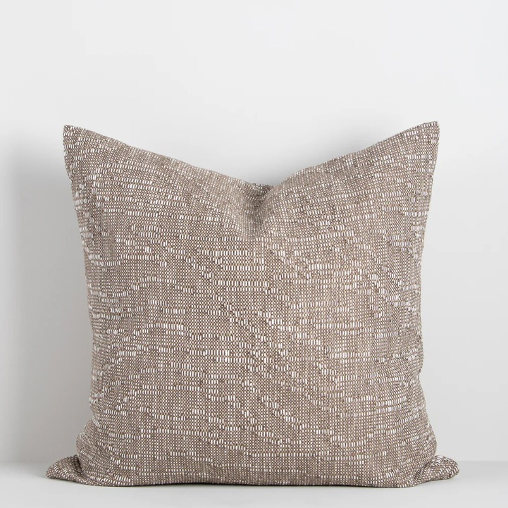 The Adler 55x55cm cushion features a subtle flecked weave in warm tones, adding refined texture and versatility to your interior styling.