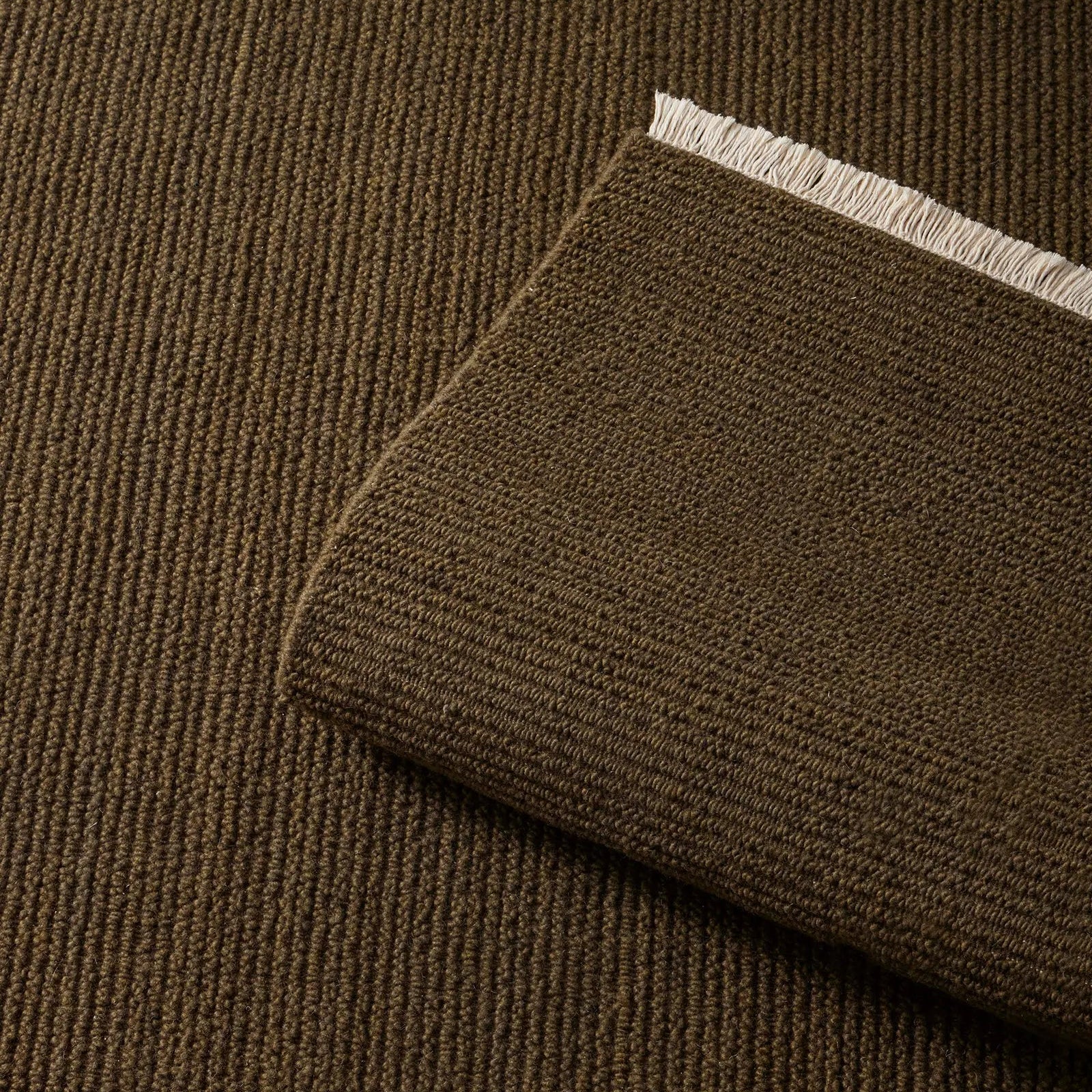 moss green rug with a textured pattern and fringe on a wooden floor. 2x3 3x4. 100% NZ wool