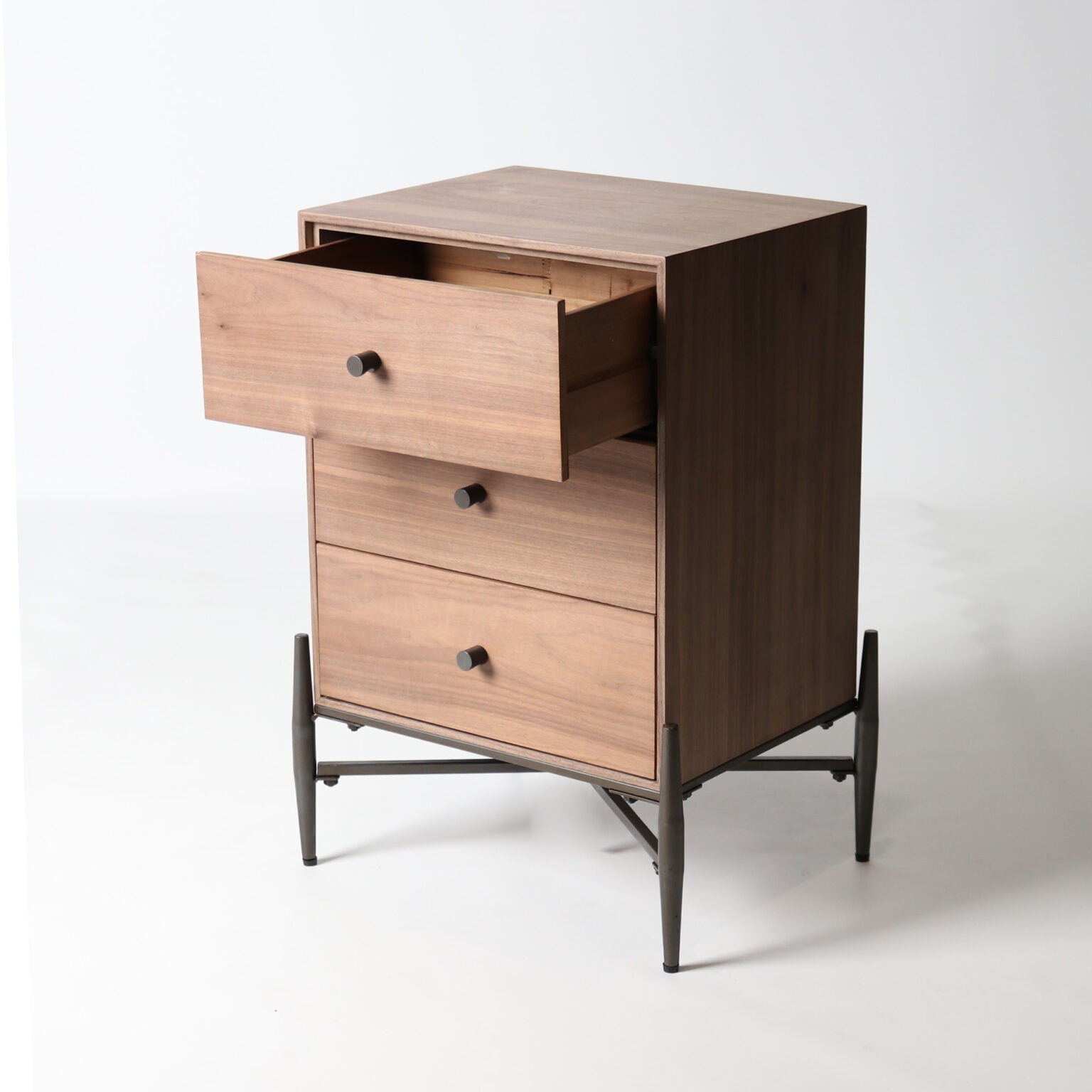 A compact and functional side table in a warm walnut finish, featuring three drawers and a sleek, modern profile.