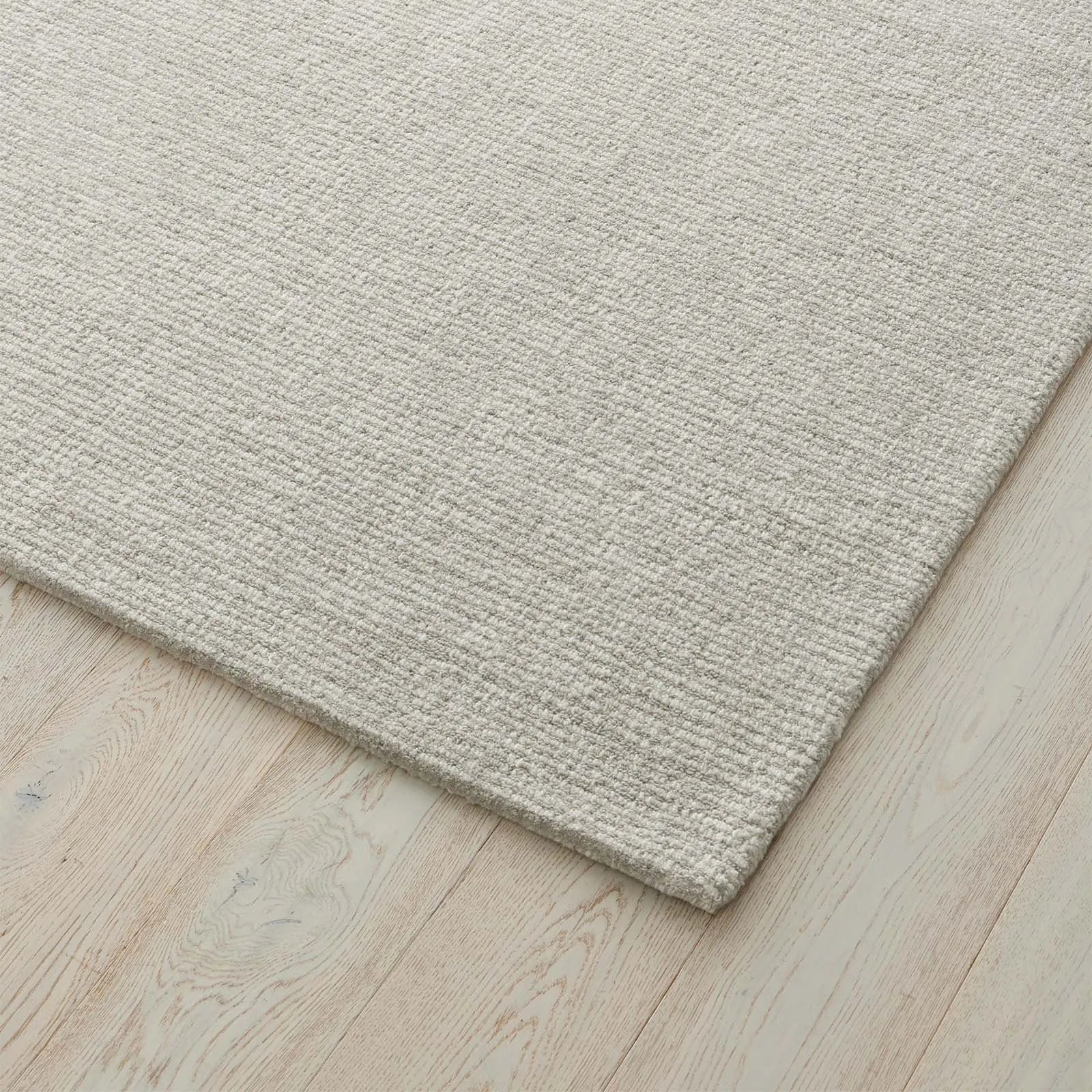 Close-up of a textured light grey rug on a wooden floor. 2x3. 100% nz wool