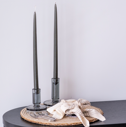 Decorative setup with black candlesticks on a textured surface against a light background