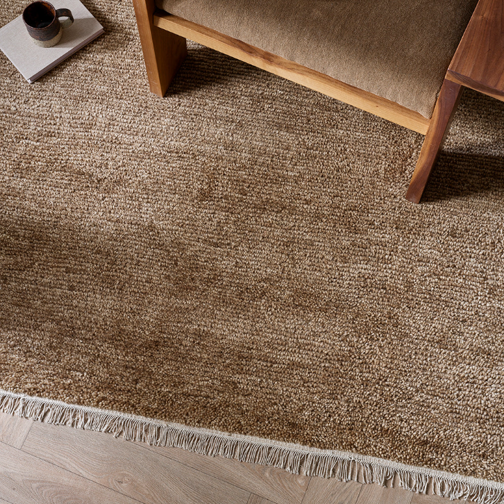 Brown textured rug with a wooden bench and coffee cup on a wooden floor. 100% NZ Wool