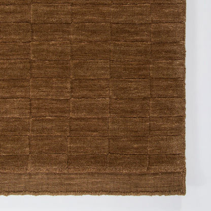 A handcrafted wool rug featuring a sculptural checkerboard design, bringing depth, texture, and bold sophistication to contemporary interiors.